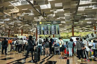Travellers queue to check-in for their flight departure at Singapore Changi airport on December 7, 2022. (Photo by Roslan RAHMAN / AFP) (Photo by ROSLAN RAHMAN/AFP via Getty Images)