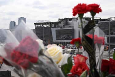 Flowers are seen left at the side of a road near the burnt-out Crocus City Hall concert venue in Krasnogorsk, outside Moscow, on March 26, 2024. At least 139 people were killed when gunmen in camouflage stormed Crocus City Hall, shooting spectators before setting the building on fire in the most fatal attack in Europe to have been claimed by Islamic State jihadists. (Photo by NATALIA KOLESNIKOVA / AFP)