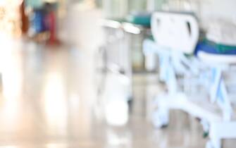 Abstract blurred hospital corridor path way with empty patient bed for background