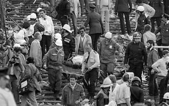 Rescuers evacuate a victim on May 29, 1985 at Heysel football stadium in Brussels after 39 people lost their lives in violent incidents, one hour before the European Champion Clubs final between Britain's Liverpool and Italy's Juventus of Turin. The tragedy occured when a wall collapsed in the stadium under the pressure of people and crushed Juventus fans as they tried to escape Liverpool supporters. 39 fans died and more than 600 were injured. (Photo by DOMINIQUE FAGET / AFP) (Photo by DOMINIQUE FAGET/AFP via Getty Images)