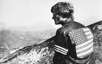 (Original Caption) 6/30/1969-Peter Fonda in a scene from the movie, "Easy Rider." He is shown with his back to the camera, wearing a jacket with the American flag on it.