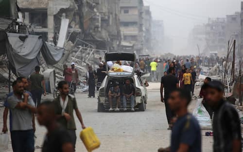 Palestinians make their way past destroyed buildings in Gaza City on October 12, 2025. Hundreds of thousands of Palestinians returned to a devastated Gaza City, after an Israel-Hamas ceasefire came into effect, and as both sides discuss implementing US President Donald Trump's 20-point plan to end the war, which calls for Hamas' disarmament and for the group not to be involved in running post-war Gaza. (Photo by Bashar TALEB / AFP)