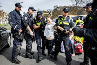 epa11262180 Swedish climate activist Greta Thunberg (C) is detained by police officers during a climate demonstration blocking the A12 highway in the Hague, the Netherlands, 06 April 2024. Thunberg joined the 37th highway blockade called by the Extinction Rebellion as new international actions against fossil subsidies were announced during the action.  EPA/RAMON VAN FLYMEN