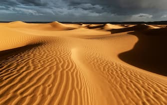 Sahara sand dunes with stormy, cloudy sky, Morocco.