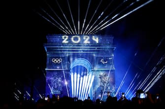 epa11051467 Fireworks and a light show behind the The Arc of Triomphe during the New Years Eve 2024 celebrations in Paris, France, 31 December 2023.  EPA/YOAN VALAT
