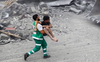TOPSHOT - A member of the Palestinian civil defence carries a wounded boy rescued from the rubble of the Tattari family home which was destroyed in an Israeli airstrike on Gaza City on October 9, 2023. Stunned by the unprecedented assault on its territory, a grieving Israel has counted over 700 dead and launched a withering barrage of strikes on Gaza that have raised the death toll there to 493 according to Palestinian officials. (Photo by Eyad AL-BABA / AFP)