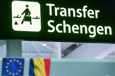 A newly installed sign pointing to Schengen transfer flights is pictured next to EU and Romanian flags, after Romania's official entry into the European area of free circulation at Otopeni's "Henri Coanda" international airport on March 31, 2024. Bulgaria and Romania joined Europe's vast Schengen area of free movement on March 31, opening up travel by air and sea without border checks after a 13-year wait. A veto by Austria however means the new status will not apply to land routes, after Vienna expressed concerns over a potential influx of asylum seekers. Despite the partial membership, the lifting of controls at the two countries' air and sea borders is of significant symbolic value. (Photo by Daniel MIHAILESCU / AFP) (Photo by DANIEL MIHAILESCU/AFP via Getty Images)