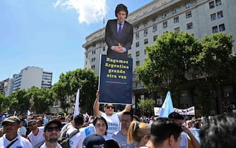 A supporter of Argentina's President-elect Javier Milei holds a banner that reads "Make Argentina great again" near the Congress, where Milei's inauguration ceremony will take place, in Buenos Aires on December 10, 2023. Javier Milei will be sworn in as Argentina's president, as the country steels itself for harsh spending cuts and economic reforms aimed at curbing rampant inflation. (Photo by Luis ROBAYO / AFP)
