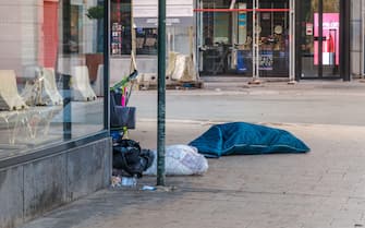 homeless Clochard sleeps right on the street in Rue Neuve in the historic center of Brussels, Belgium, january 1, 2020