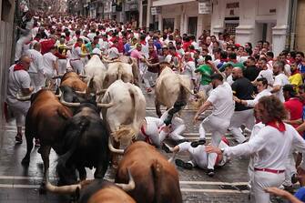 Participants fall down as they run with bulls during the first "encierro" (bull-run) of the San Fermin festival in Pamplona, northern Spain, on July 7, 2023. Thousands of people every year attend the week-long festival and its famous 'encierros': six bulls are released at 8:00 a.m. evey day to run from their corral to the bullring through the narrow streets of the old town over an 850 meters (yard) course while runners ahead of them try to stay close to the bulls without falling over or being gored. (Photo by CESAR MANSO / AFP) (Photo by CESAR MANSO/AFP via Getty Images)