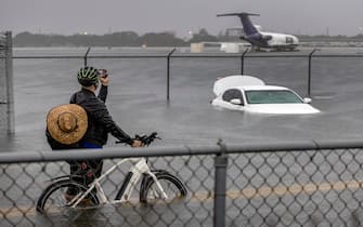 epa10571677 A person takes pictures of a car that is stranded in flood water on Fort Lauderdale International Airport's West Perimeter road in Fort Lauderdale, Florida, USA, 13 April 2023. Heavy rains in the past days produced flooding in the lower areas of the Miami-Dade and Broward counties.  EPA/CRISTOBAL HERRERA-ULASHKEVICH