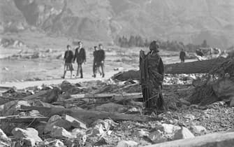 People walk past a lone, standing statue among the ruins, Longarone, near the Vajont Dam in the Piave Valley, Italy, early October, 1963. On October 9, a landslide in the dam basin caused a wave more than 800 feet high to overtop the dam and flood the valley below--five villages were completely destroyed, more than 2000 people were killed, and thousands more were left homeless and displaced. (Photo by Archivio Cameraphoto Epoche/Getty Images)