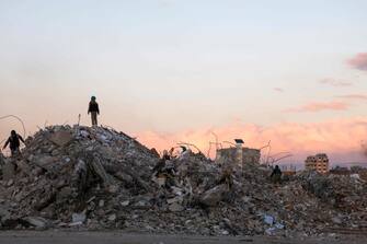 Syrians search building rubble for items to salvage in the regime-controlled town of Jableh in the province of Latakia, northwest of the capital, on February 10, 2023, in the aftermath of a deadly earthquake. (Photo by Karim SAHIB / AFP)