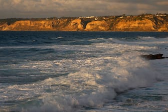 SAN DIEGO, CALIFORNIA - FEBRUARY 2: Waves crash in the Pacific Ocean at sunset with the bluffs above Black's Beach in the background on February 2, 2024 in San Diego, California.  (Photo by Kevin Carter/Getty Images)