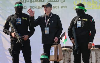 Palestinian militant group Hamas fighters escort American-Israeli hostage Keith Siegel on a stage before handing him over to a Red Cross team in Gaza City on February 1, 2025, as part of the fourth hostage-prisoner exchange. (Photo by Omar AL-QATTAA / AFP)