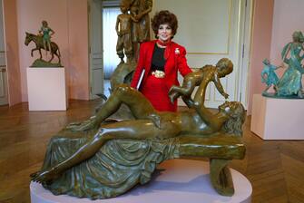 L'ancienne actrice italienne Gina Lollobrigida pose derriÃ¨re l'une de ses sculptures, le 09 octobre 2003 Ã  l'HÃ´tel de la Monnaie Ã  Paris, lors de l'inauguration de son exposition qui regroupe une quarantaine de piÃ¨ces de toutes tailles, en marbre ou en bronze. (Photo by Jack GUEZ / AFP) (Photo by JACK GUEZ/AFP via Getty Images)