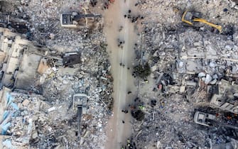 epa10460174 An aerial picture taken by drone shows excavators work on a collapsed building after a powerful earthquake in Hatay, Turkey, 11 February 2023. More than 24,000 people have died and thousands more are injured after two major earthquakes struck southern Turkey and northern Syria on 06 February. Authorities fear the death toll will keep climbing as rescuers look for survivors across the region.  EPA/ERDEM SAHIN