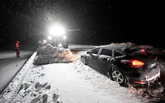 Employees cleared snow with wheel loaders as drivers are evacuated with the Home Guard's tracked vehicle at Ekerodsrasten on the E22 between Horby and Kristianstad in southern Sweden, on the night of January 4, 2024. Up to 300 cars stuck in a queue due to large amounts of snow that fell on the roadway and limited access, according to the police. (Photo by Johan Nilsson/TT / TT NEWS AGENCY / AFP) / Sweden OUT