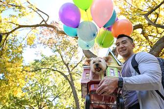 NEW YORK, NEW YORK - OCTOBER 22: Billy Chan holds his dog, Allie the terroir, dressed as UP during the Annual Tompkins Square Halloween Dog Parade on October 22, 2022 in New York City. The parade returned to Tompkins Square Park after being relocated last year. Â (Photo by Alexi Rosenfeld/Getty Images)