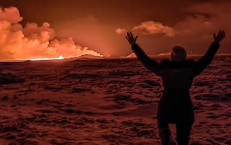 A local resident watch smoke billow as the lava colour the night sky orange from an volcanic eruption on the Reykjanes peninsula 3 km north of Grindavik, western Iceland on December 18, 2023. A volcanic eruption began on Monday night in Iceland, south of the capital Reykjavik, following an earthquake swarm, Iceland's Meteorological Office reported. (Photo by Kristin Elisabet Gunnarsdottir / AFP) (Photo by KRISTIN ELISABET GUNNARSDOTTIR/AFP via Getty Images)