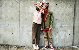 Portrait of couple kissing while hidden behind bouquet of flowers