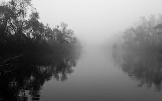 "Fog and rusty sctructures creates a scary mood in this misterious view over a placid river. Shot in Fiume Po, Venice, Italy.Black toned, some grain visible."