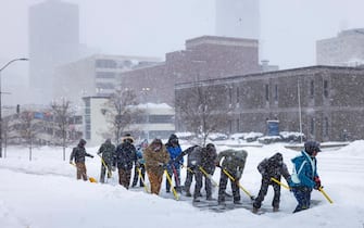 epa11072577 Day laborers shovel snow off a sidewalk  during a blizzard in downtown Des Moines, Iowa, USA, 12 January 2024. Candidates who would normally be criss-crossing Iowa in the final days before its first-in-the-nation caucus on 15 January are cancelling many of their events today, as winter weather is creating unsafe travel conditions.  EPA/JIM LO SCALZO