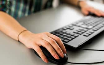 Close up of a woman using a computer keyboard and a mouse