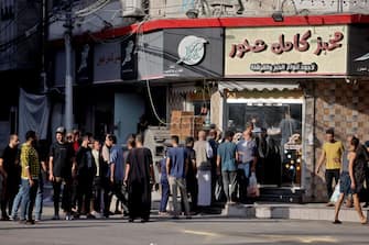 Palestinians line up outside a shop in Gaza City after Israeli air strikes, on October 13, 2023. Israel has called for the immediate relocation of 1.1 million people in Gaza amid its massive bombardment in retaliation for Hamas's attacks, with the United Nations warning of "devastating" consequences. (Photo by MOHAMMED ABED / AFP) (Photo by MOHAMMED ABED/AFP via Getty Images)