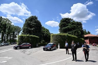 Carbinieri stand guard next to their vehicles parked at the entrance of Villa San Martino (C), the residence of Italian businessman and former prime minister Silvio Berlusconi, as mourners gather to lay flowers following his death, in Arcore, northern Italy, on June 12, 2023. Italy's former prime minister Silvio Berlusconi has died aged 86, his spokesman confirmed to AFP on June 12, 2023. The billionaire media mogul was admitted to a Milan hospital on June 9 for what aides said were pre-planned tests related to his leukemia. (Photo by Piero CRUCIATTI / AFP)