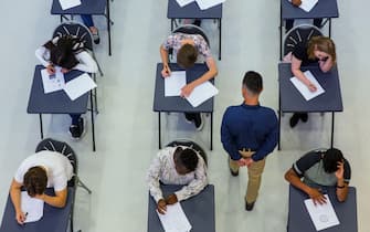 High school teacher supervising students taking exam at desks
