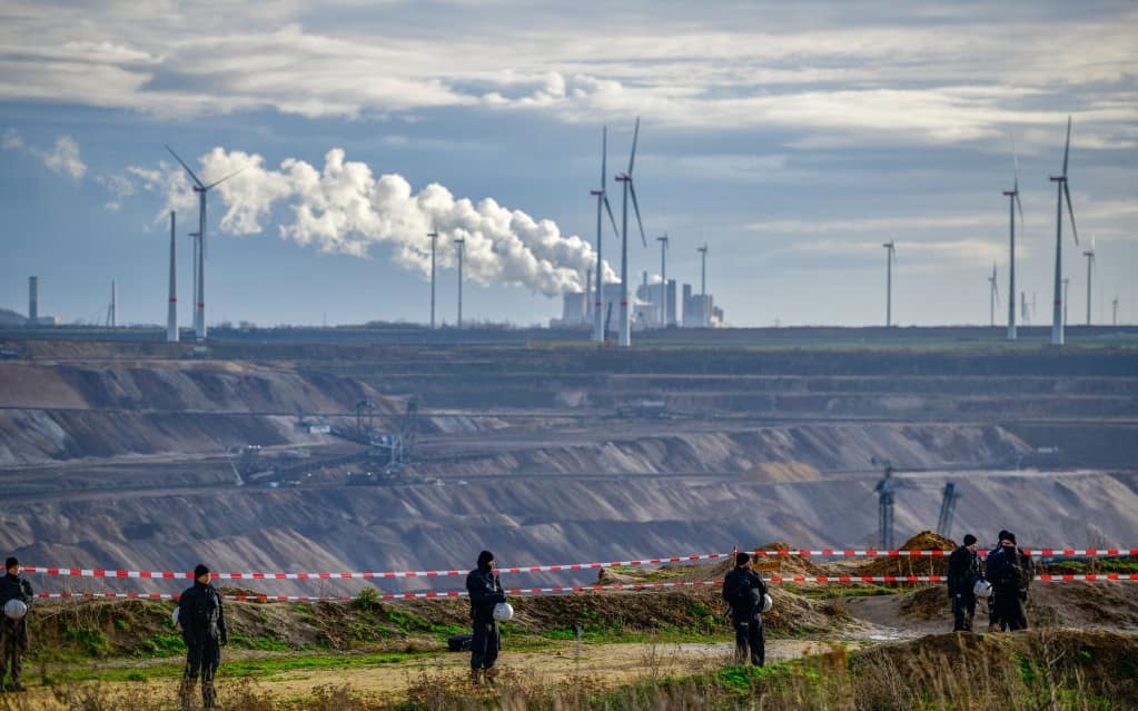 ERKELENZ, GERMANY - JANUARY 8: Police officers stand as the Neurath coal-fired power plant stands behind close to the settlement of Luetzerath next to the Garzweiler II open cast coal mine on January 8, 2023 near Erkelenz, Germany.  Police are preparing to evict environmental activists who have occupied the abandoned Luetzerath settlement. The activists are seeking to prevent Luetzerath's demolition that will make way for an expansion of the Garzweiler coal mine. Governmental authorities have approved the demolition and the coal mine expansion, while at the same time announcing an accelerated phase out of coal-fired energy production in the state of North Rhine-Westphalia by 2030. Other nearby settlements that were also slated for demolition will now be spared, though critics point out that Germany has sufficient energy production capacity and does need the coal lying beneath Luetzerath. (Photo by Sascha Schuermann/Getty Images)