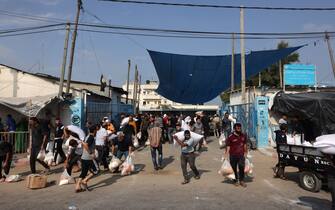 Palestinians storm a UN-run aid supply center, that distributes food to displaced families following Israel's call for more than one million residents in northern Gaza to move south for their safety, in Deir al-Balah on October 28, 2023, amid the ongoing battles between Israel and the Palestinian group Hamas. Thousands of civilians, both Palestinians and Israelis, have died since October 7, 2023, after Palestinian Hamas militants based in the Gaza Strip entered southern Israel in an unprecedented attack triggering a war declared by Israel on Hamas with retaliatory bombings on Gaza. (Photo by MOHAMMED ABED / AFP) / "The erroneous mention[s] appearing in the metadata of this photo by MOHAMMED ABED has been modified in AFP systems in the following manner: [Storm] instead of [Collect boxes and and bags from]. Please immediately remove the erroneous mention[s] from all your online services and delete it (them) from your servers. If you have been authorized by AFP to distribute it (them) to third parties, please ensure that the same actions are carried out by them. Failure to promptly comply with these instructions will entail liability on your part for any continued or post notification usage. Therefore we thank you very much for all your attention and prompt action. We are sorry for the inconvenience this notification may cause and remain at your disposal for any further information you may require." (Photo by MOHAMMED ABED/AFP via Getty Images)