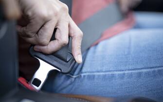 Car safety concept; Close up of hand woman pulling seat belt in her car.