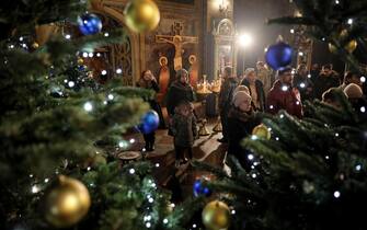 epa11043326 People stand next to a Christmas tree as they attend a Christmas Eve prayer service at the St. Michael's Golden-Domed Cathedral in  Kyiv, Ukraine, 24 December 2023. Ukraine is celebrating Christmas on December 25 for the first time this year according to the Western calendar. Ukrainian President Volodymyr Zelensky signed a law in July to move the celebration from the Russian Orthodox calendar.  EPA/OLEG PETRASYUK