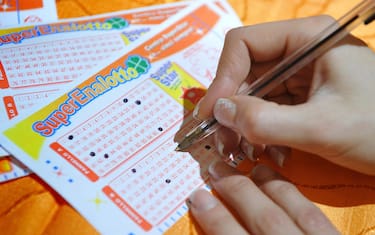 2010 年 9 月 5 日，一名彩民在罗马一家酒吧里填写六合彩彩票，等待今天的开奖。安莎社/克劳迪奥·佩里