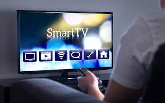 Man watching smart tv. Choosing movie or series from the menu. Person holding remote control. User interface on television screen.