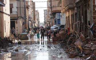 epa11693902 Residents walk through a damaged street resulting from flooding in the Municipality of Catarroja, Valencia, Spain, 31 October 2024. At least 95 people died in the province of Valencia and neighboring provinces following floods caused by the DANA (high-altitude isolated depression) phenomenon impacting the eastern part of the country.  EPA/MANUEL BRUQUE