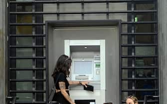 Una donna mentre preleva dei soldi dallo sportello Bancomat di una banca