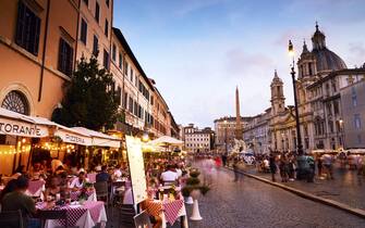 Italy, Lazio, Rome, People dining outside in Piazza Navona in twilight