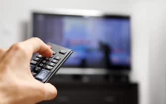hand hold remote control in front of tv