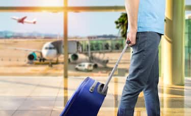 Shot of a young man walking with her luggage through the departure lounge of an airport