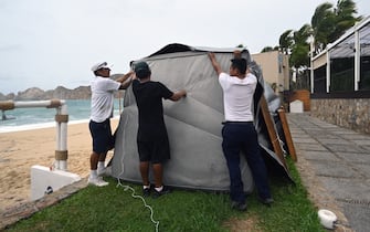 Restaurant employees put a protection fabric on a restaurant in front the Medano beach before the arrival of hurricane Hilary at Los Cabos resort in Baja California state, Mexico on August 18, 2023. Hurricane Hilary strengthened into a major storm in the Pacific on Friday and was expected to further intensify before approaching Mexico's Baja California peninsula over the weekend, forecasters said. (Photo by ALFREDO ESTRELLA / AFP) (Photo by ALFREDO ESTRELLA/AFP via Getty Images)