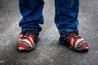 CONCORD, NH - January 19: Trump supporter Edward X. Young, right, wears Trump branded sneakers while waiting in line ahead of Trump's arrival to the Grappone Center. This will be Young's 67th Trump rally. (Photo by Erin Clark/The Boston Globe via Getty Images)