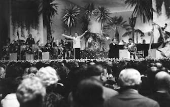 The Italian singer Domenico Modugno is singing the song Nel blu dipinto di blu, with raised and open arms, at the 8th edition of Sanremo Italian Song Festival; the song, known with the title Volare, wins at the festival. Sanremo (IM), Italy, February 1, 1958. (Photo by Mondadori via Getty Images)