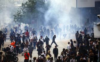 epa10717450 People walk amid tear gas as they clash with French riot police on the sidelines of a march in the memory of 17-year-old Nahel, who was killed by French Police in Nanterre, near Paris, France, 29 June 2023. Violence broke out after the police fatally shot a 17-year-old during a traffic stop in Nanterre on 27 June. According to the French interior minister, 31 people were arrested with 2,000 officers being deployed to prevent further violence.  EPA/YOAN VALAT