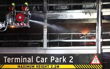 Firemen battle a fire at London's Luton Airport which caused a partial collapse of a parking structure in Luton on October 11, 2023. Five people, including four firefighters and an airport employee, were admitted to hospital, according to the local ambulance service. (Photo by HENRY NICHOLLS / AFP)