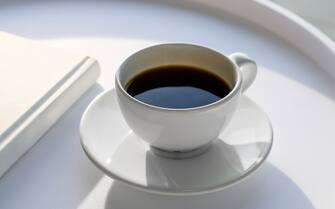 White coffee cup and a white book on a white coffee table