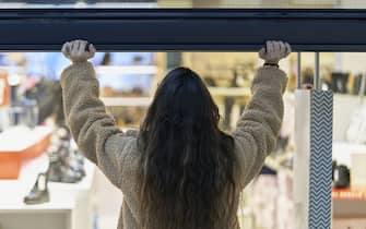 Back view of a woman closing or open a store at shopping mall center.