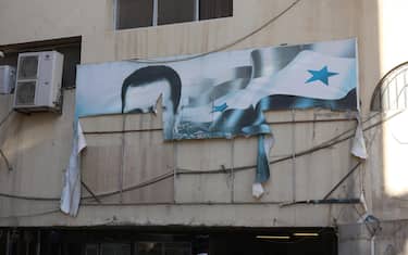 epa11765465 A torn banner depicting the picture of Bashar al-Assad on a building after rebels took over Damascus, Syria, 08 December 2024. Syrian rebels entered Damascus on 08 December 2024 and announced in a televised statement the 'Liberation of the city of Damascus and the overthrow of Bashar al-Assad,' as well as the release of all the prisoners. The rebels also urged the Syrian armed forces to leave Syrian public institutions, which will stay under the control of the outgoing Syrian prime minister until the official handover ceremony  EPA/MOHAMMED AL RIFAI